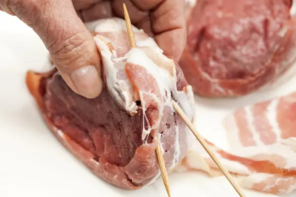 Colocando palitos de dentes para garantir o bacon em torno dos medalhões de lombo de vaca — Fotografia de Stock