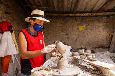 RAQUIRA, COLOMBİA - Şubat 2021. Kolombiya 'nın Cundinamarca bölgesinde bulunan Raquira şehrindeki geleneksel bir fabrikada çömlekçiler çarkında seramik makaleler yapan adam.
