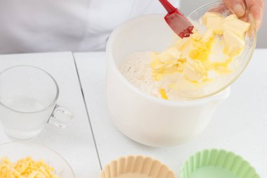 Kıdemli kadın lezzetli bir peynirli ve jambonlu tart için hamur hazırlıyor.