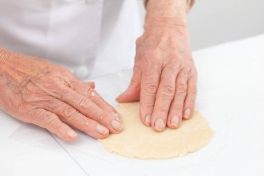 Kıdemli kadın lezzetli bir peynirli ve jambonlu tart için hamur hazırlıyor.