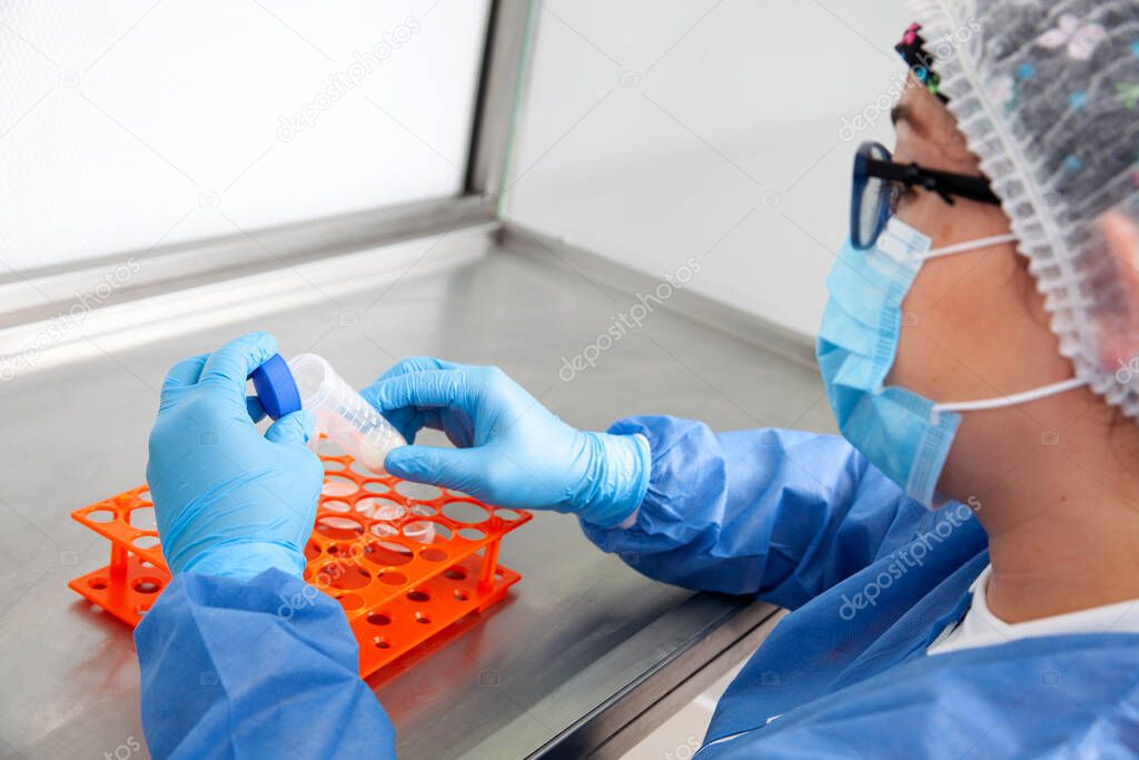 Young female scientist working in a safety laminar air flow cabinet at laboratory