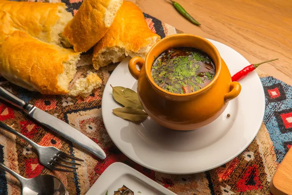 Hot, spicy soup and chicken broth with herbs and spices in a clay pot — Stock Photo, Image