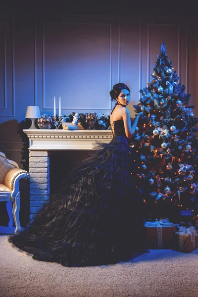Hermosa modelo chica en la víspera de Navidad cerca del árbol de Navidad con regalos . — Foto de Stock
