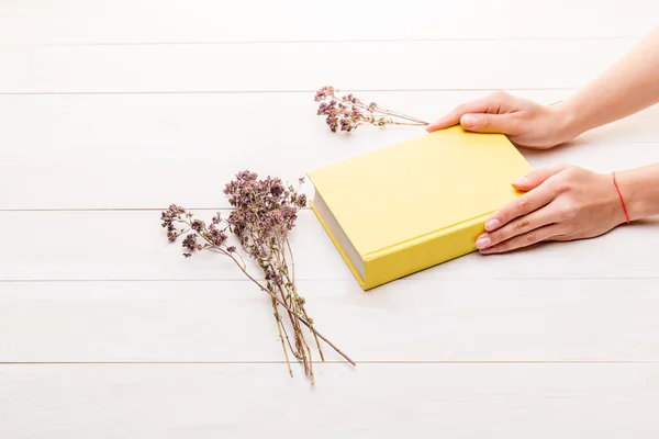 Female hands holding a closed yellow book