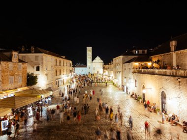 Kalabalık tarihi Hvar şehir meydanının gece fotoğrafı. Kilise ve taş binalar, popüler turistik gece hayatı merkezleri..