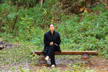 Genç, güzel, esmer bir öğrenci elinde dizüstü bilgisayarla bankta sakura 'nın altında oturuyor. Yüksek kalite fotoğraf