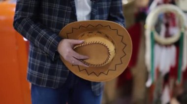 Erkek el şapka dükkanında bir kovboy şapkası tutuyor. Texas 'ın dükkanında el yapımı kovboy şapkası.