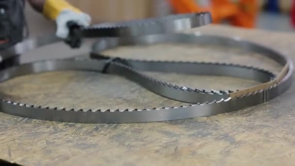 Spare parts for industrial sawmill. The teeth of a saw steel blades just now comes from machine for welding industrial sawmill blades. The worker collects saw blades all together. Close up — Stock Video