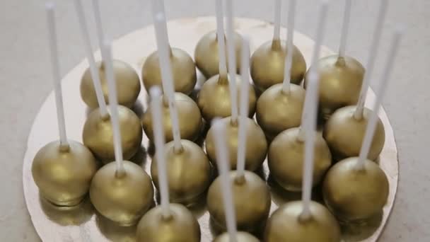 Veel goudkleurige heerlijke cakepops. Zelfgemaakte dessert ballen met chocolade topping binnen — Stockvideo
