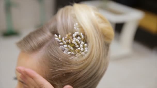 美容師は結婚式の前に花嫁を準備しています 若いブロンドの髪の女性の髪に装飾を取り付ける美容師 — ストック動画