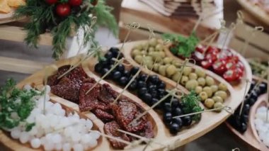Tatil büfesinde farklı aperatiflerle servis edilen tipik tabaklar. Zeytinli ahşap tabak, dolma biber, soğan turşusu, kurutulmuş domates ve otlar..