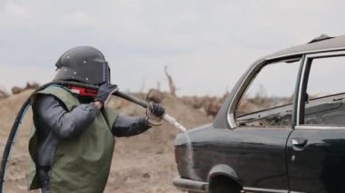 Arabanın metal yüzeyini zımparalayan işçiler