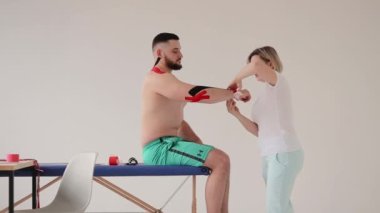 Doktor bir adamın dirseğine özel bir tedavi bandı yapıştırıyor.