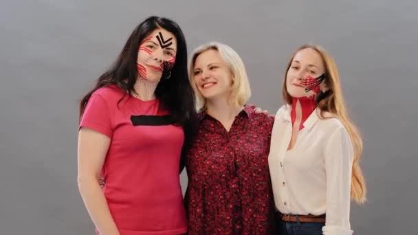Kinesio Taping 两个脸上带着红色和黑色动画录影带的女孩拥抱着她们的美容师大师 感谢她的治疗 动态变化学概念 — 图库视频影像