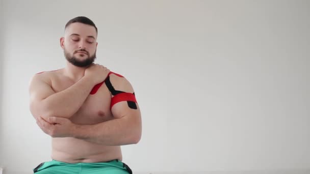 치료사가 환자의 어깨에 신장결석 테이프를 줄인다 — 비디오
