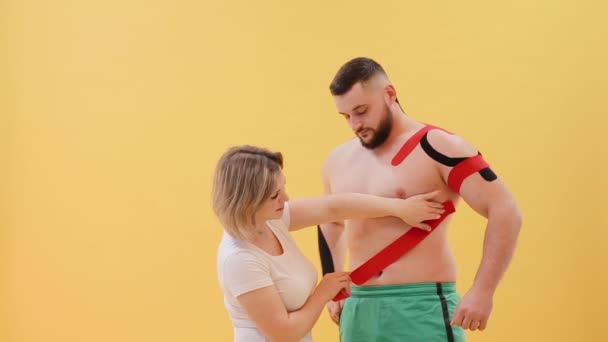 Female Therapist Applying Kinesiology Tape Man Abdomen Yellow Background Woman — Stock Video