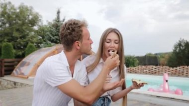 Couple eating pizza and feeding each other. Tasting pizza from delivery
