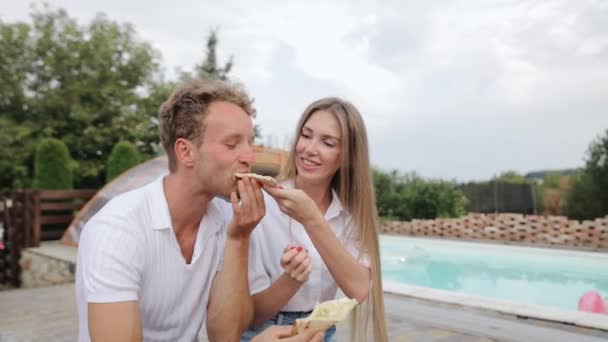 Young Woman Feeding Her Laughing Friend Slice Cheesy Pizza Poolside — Αρχείο Βίντεο