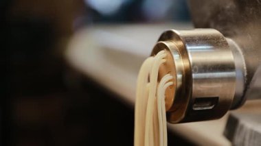 Makineden çıkan fettuccine 'i yakın çekimde, şef alır ve keser. Makarna makinesi, ev yapımı makarna. Spagetti üretimi, kurutulmaya hazır. Yavaş çekim