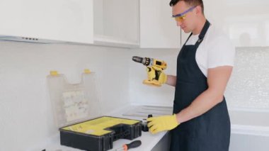 Elektrikli tornavidayı ayarlayan bir adama yaklaş. Aküyü alır ve skrewdriver 'ın içine yerleştirir.