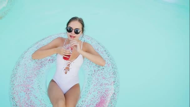 快乐的微笑的女人在游泳池里喝鸡尾酒 女孩正在游泳池的充气床垫上喝果汁 — 图库视频影像