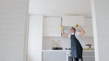 Marangoz yeni eve mobilya kuruyor. Beyaz rengin modern mutfağında marangoz onarım ve montaj dolabı.
