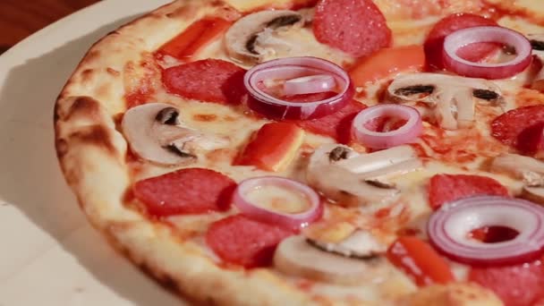 Pizza bien cocida con queso derretido, cebolla, champiñones, salami y peper rojo. Pizza típica italiana llamada capricciosa en el plato de madera — Vídeos de Stock
