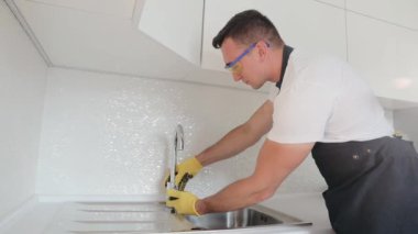 Üniformalı profesyonel bir tesisatçı, vincin mutfağa yerleştirilme kalitesini garanti eder. Mutfak lavabosunun üzerine yeni bir musluk kuruyorum.