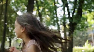 Neşeli genç bir kız, güzel yeşil bir parkta gününün tadını çıkarıyor. Güneş ışığında koşuyor ve etrafı ağaçlarla çevrili. Cennet sahnesi çocukluk masumiyetinin ve mutluluğun özünü yakalar.