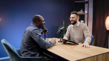 İki farklı adam aynı kahkahayı paylaşıyor, canlı yayın içeriği yaratıyorlar. Stüdyo mikrofonlarıyla görüşüp fikirleri tartışıyorlar.