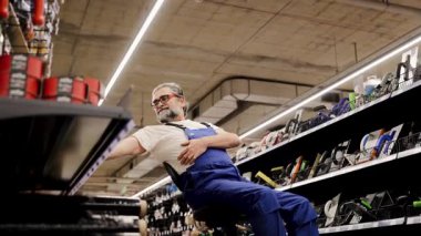 İnşaat işçisi bir inşaat malzemeleri dükkanında araç seçiyor. Ev tadilatı planlayan, yenileme projesi için donanım seçen bir adam. Satış mağazası müdürü envanter görevi yapıyor