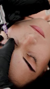 Kalıcı göz kalemi dövmesi yaptıran bir kadın. Dikey video