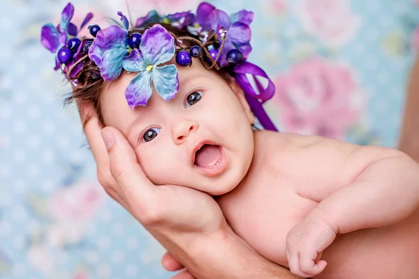 Portret van een mooi lachende babymeisje in een krans van bloemen — Stockfoto
