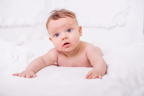 Маленький милый голый ребенок смотрит в камеру на белой стене . — стоковое фото
