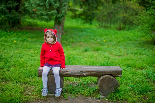 Малышка сидит на скамейке — стоковое фото