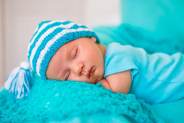 The baby sleeps on the tummy in a striped cap with a pompon — Stock Photo, Image