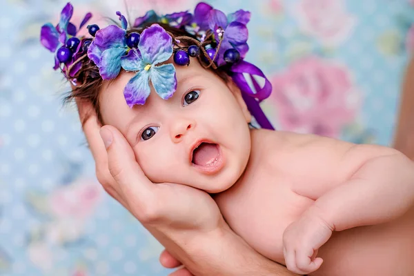 Ritratto di bambina con una corona di fiori viola sulla testa su uno sfondo chiaro — Foto Stock