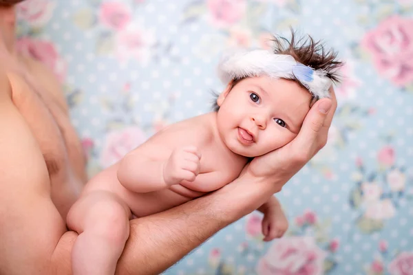 1 mês bebê menina olhando e sorrindo para a câmera. Bebê nu com coroa de penas na cabeça — Fotografia de Stock