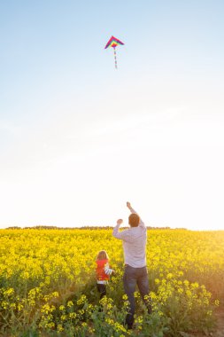 Baba ve kızı bir uçurtma batımında denize indirmek