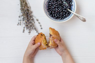 Bir yabanmersini kase, lavanta ve çörek beyaz bir arka plan üzerine açık kırma çocuk elleri çiçekler düz bir lay