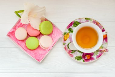 Renkli macaron ve çay beyaz ahşap zemin üzerinde. Düz yatıyordu