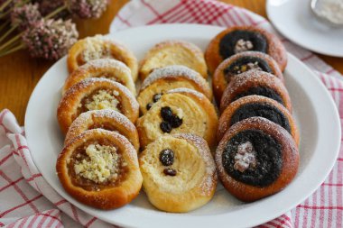 Close-up of traditional Czech festive kolache with apple, curd cheese and poppy seed filling sprinkled with powdered sugar served on plate, detail of sweet homemade bakery pastry