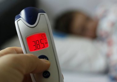 Alnında termometre olan, yüksek vücut sıcaklığında, kırmızı ekranlı ve hasta bir çocuk olan bir kadının elini tut. Covid 19 kavramı, virüs enfeksiyonu, hastalık, ateş, evde tıbbi bakım