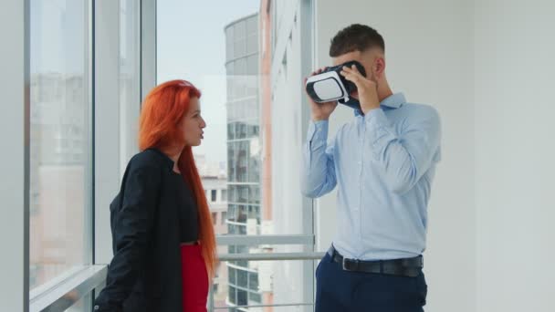 Los trabajadores de oficina se divierten durante un descanso junto a la ventana. Un hombre con gafas vr y una mujer riéndose de su marido. — Vídeos de Stock