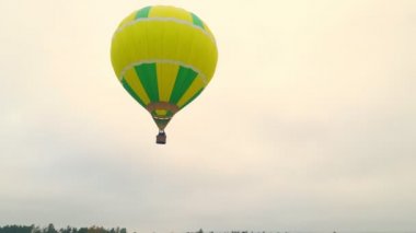 Bulutlu bir günde Balon uçuşunun hava aracı görüntüsü. Yerin üstünde alçaktan uçan bir balon. Güz balonu muhteşem göller ve ormanlar üzerinde uçuyor..