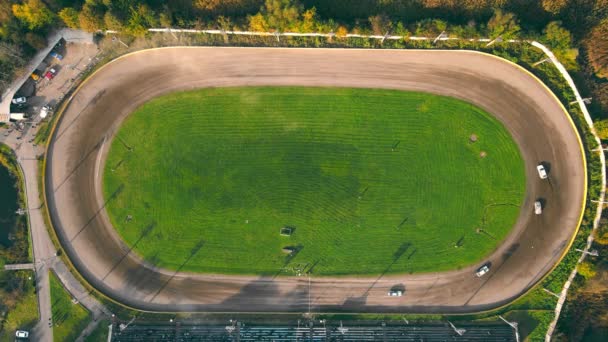 Pemandangan udara di atas Races di arena pacuan kuda. Mobil-mobil yang melaju dalam lingkaran melayang di tikungan bersaing untuk tempat pertama dalam balap mobil. — Stok Video