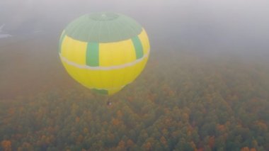 Yoğun sis ve bulutlu havada, sonbahar ormanında uçan balon, yukarıdan görünüyor..