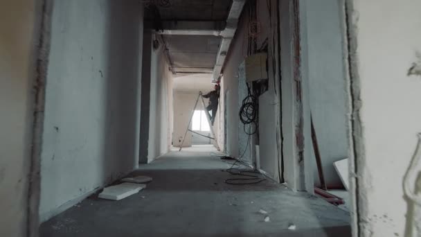 Silhuett av en byggnadsarbetare som lägger ventilationskanaler. Arbetstagare som arbetar på stege i en ny byggnad på en byggarbetsplats. — Stockvideo