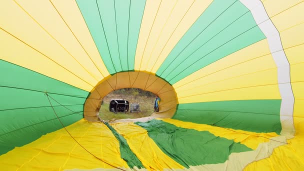 Globo desde el medio. Los viajeros inflan el globo con aire caliente y se preparan para volar en un globo por encima de las nubes. Preparación para un vuelo en globo — Vídeos de Stock