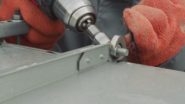 Cerrajero trabajador de primer plano aprieta tuerca con destornillador primer plano. El maestro aprieta las planchas tuercas metálicas a la producción. — Vídeo de stock